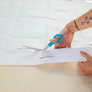 Vancillary sprinter template for 2019 2020 2021 2022 2023 2024 sprinter vans being cut by scissors held by a woman with a wrist tattoo.